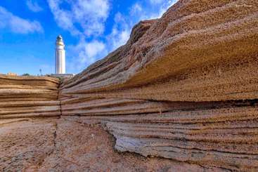 La imagen representa un paisaje sereno en el que aparece una masa de agua con un acantilado prominente, probablemente un río, y una zona cubierta de hierba, evocando una sensación de belleza natural y tranquilidad.