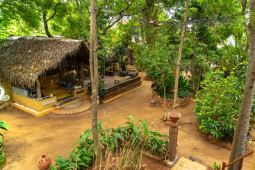 The image depicts a serene outdoor setting, featuring a building with a sloping roof, surrounded by trees and a body of water, evoking a sense of tranquility and natural beauty.