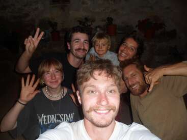 Six amis, dont un enfant, sourient pour un joyeux selfie en intérieur. Ils font des signes de paix et des gestes de la main, créant ainsi une atmosphère chaleureuse, heureuse et détendue.