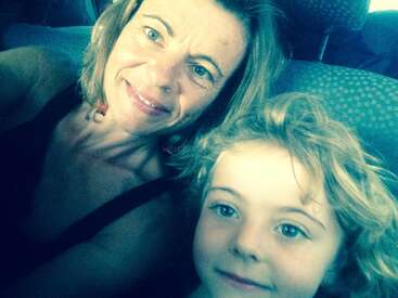 The image shows a woman and a child posing for a selfie, with the woman on the left and the child on the right, both smiling.