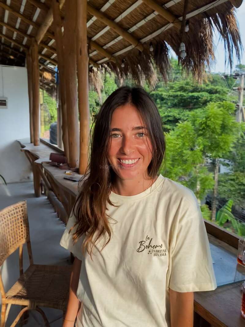 The image depicts a woman with long brown hair, wearing a white t-shirt with the words "la Boheme" and "UNAWATUNA SRI LANKA" printed on it.