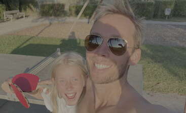 La imagen muestra a un hombre y una joven posando para un selfie, con el hombre sosteniendo una pala de ping pong y la chica una raqueta de ping pong.