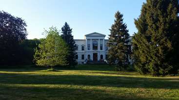 The image depicts a large house with a sprawling yard, featuring a prominent tree and a well-manicured lawn, set against a backdrop of a serene and peaceful outdoor environment.