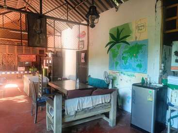 Esse quarto aconchegante e rústico apresenta móveis feitos à mão, arte vibrante na parede, incluindo um mapa-múndi, uma pequena geladeira, decorações ecléticas e luz solar natural e quente iluminando o espaço.