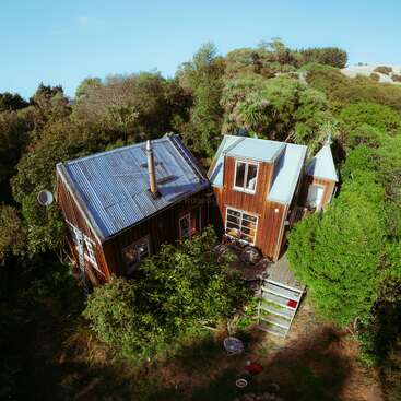 The image depicts a serene scene of a house with a large yard, featuring a tree and a fence, set against a backdrop of a clear blue sky and a grassy field.