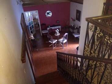 Das Bild zeigt einen gemütlichen Essbereich von einer Treppe mit verziertem Geländer aus gesehen. Es gibt einen runden Tisch, mehrere Stühle und eine rosa Akzentwand.