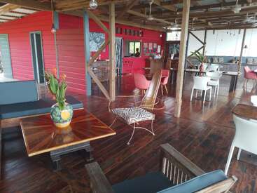 The image depicts a spacious room with dark wood floors and furniture, featuring a vibrant red wall and a wooden ceiling, exuding a warm and inviting atmosphere.
