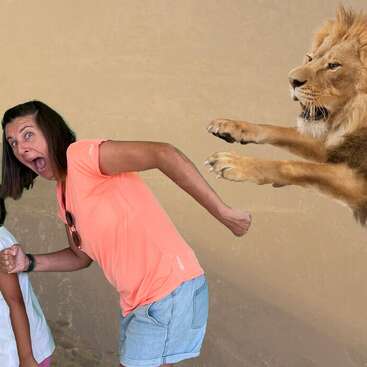 Una mujer con una camiseta color melocotón finge estar asustada, como si huyera de un león que se abalanza sobre ella. La escena parece estar montada o editada con intención humorística.