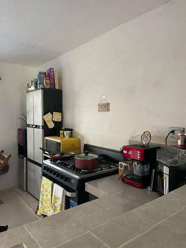 Una acogedora cocina equipada con fogones, ollas, cafetera, microondas, nevera y diversos utensilios. El espacio está decorado con toques de color amarillo brillante y un letrero que dice «Cocina».