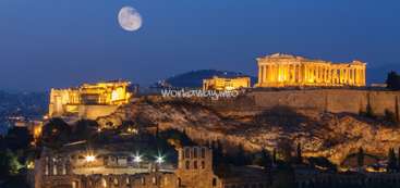 L'image représente l'Acropole d'Athènes, en Grèce, de nuit, avec la lune visible dans le ciel au-dessus de la structure antique.