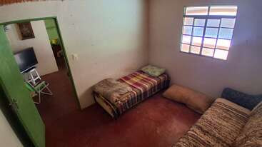 Cette chambre confortable comprend deux lits simples avec une parure de lit à motifs, une fenêtre aux vitres colorées et une porte verte donnant sur un petit coin salon.
