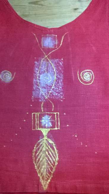 L'image représente un tissu rose avec un motif doré, comportant une plume, un rectangle et d'autres formes. Il s'agit peut-être d'un projet fait à la main ou d'un projet de bricolage sur une table.