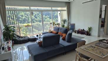 Dieses helle Wohnzimmer hat ein modernes blaues Sofa, große Fenster mit einem tollen Blick auf den Wald, viele Zimmerpflanzen, eine gemütliche Einrichtung und ein Brettspiel auf dem Tisch.
