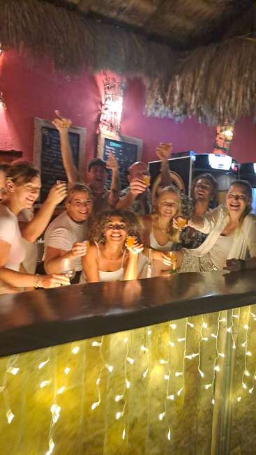 Um grupo de amigos comemora junto em um bar animado. Eles brindam com bebidas, sorrindo radiantes. A iluminação aconchegante e o clima festivo criam um momento alegre e inesquecível.