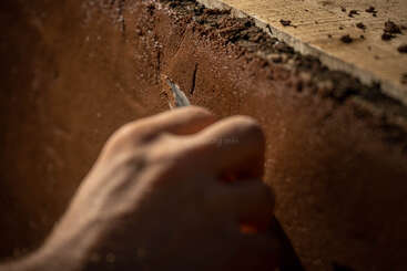 La imagen muestra las manos de una persona sujetando una paleta, con una pared de yeso u hormigón al fondo, probablemente durante el proceso de construcción o renovación de una casa.