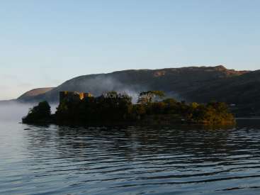 The image depicts a serene landscape featuring a body of water, a distant island, and a mountainous backdrop, with a subtle watermark overlay.