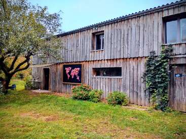 Auf dem Bild sieht man ein rustikales Holzhaus mit einer Karte, die draußen aufgehängt ist. Grünes Gras, Büsche und ein Baum machen die friedliche, naturverbundene Umgebung komplett.