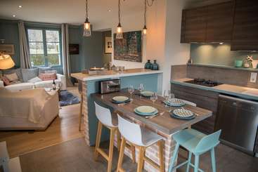 L'image montre une cuisine moderne avec une table à manger, qui présente un mélange harmonieux de tons blancs et boisés, complétés par un comptoir élégant et un dosseret stylisé. L'espace dégage une impression de chaleur et de sophistication.