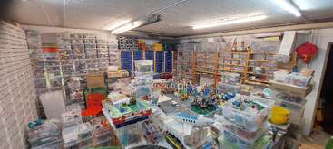 Dieses Bild zeigt einen gut organisierten Raum mit zahlreichen Plastikschubladen und -behältern, in denen LEGO Teile und Modelle aufbewahrt werden - perfekt für den Arbeitsbereich eines LEGO Enthusiasten.