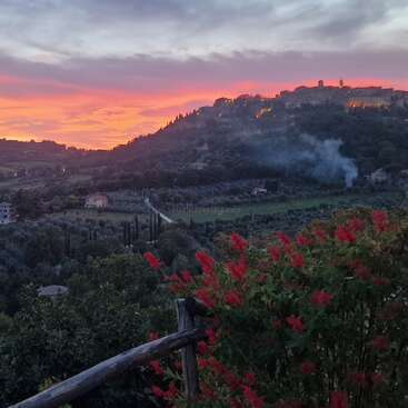 La imagen representa un paisaje sereno con colinas onduladas, una carretera serpenteante y una masa de agua, que evoca una sensación de tranquilidad y belleza natural. Es probable que la escena esté ambientada en una zona rural.