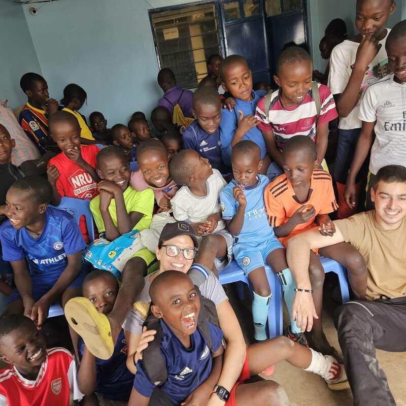 Un grupo de niños alegres y dos adultos se sientan juntos en el interior, sonriendo, riendo y disfrutando de la compañía de los demás, creando un ambiente cálido y animado.