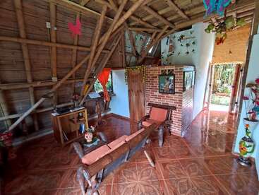 Cette chambre confortable est dotée de murs en bambou, d'un mobilier rustique en bois, d'éléments décoratifs et de carreaux aux couleurs vives. La lumière naturelle pénètre à flots par la porte, révélant un magnifique jardin à l'extérieur.