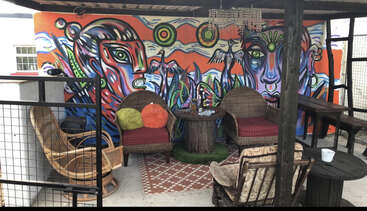 The image depicts a room with a table and chairs, featuring a large window on the left side and a door on the right side, with a wall in the background.