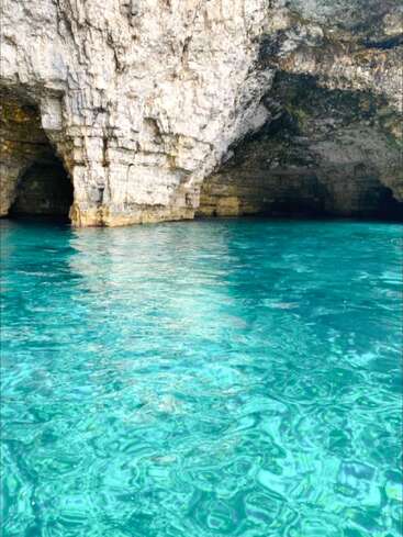 Une eau turquoise cristalline vient doucement lécher les grottes calcaires escarpées. La lumière du soleil illumine les teintes vives, créant un sanctuaire côtier serein, accueillant et magique. Un paradis caché de la nature.