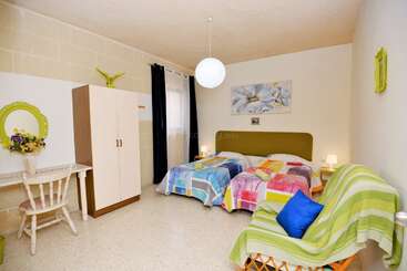 Cette chambre confortable comprend deux lits simples recouverts de couvertures colorées en patchwork, un canapé, une armoire, un bureau, une décoration lumineuse, des fleurs fraîches et un éclairage tamisé.