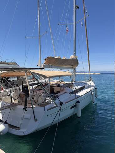 Un magnifique voilier blanc baptisé « Everlasting Zen », amarré dans une marina aux eaux bleues et limpides, sous un ciel radieux et sans nuage, prêt à partir à l'aventure.