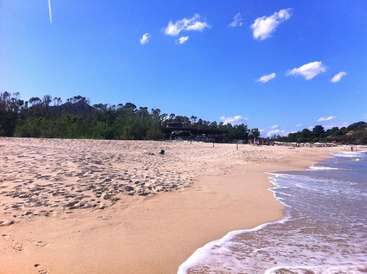 The image depicts a serene beach scene with a sandy shore, gentle waves, and a clear blue sky, evoking a sense of tranquility and relaxation.