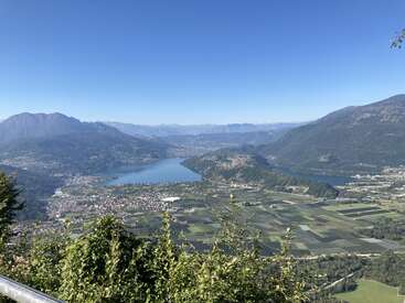 Uma vista de tirar o fôlego de um lago azul cercado por vales verdes, cidades e montanhas altas sob um céu azul claro e brilhante. Tranquilo e pitoresco.