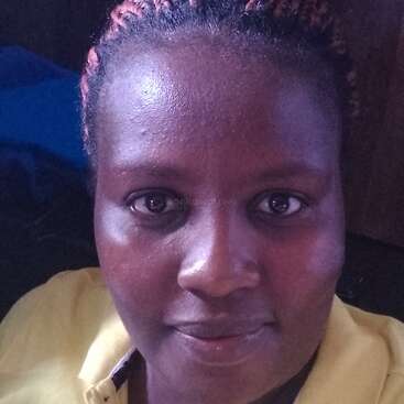 The image depicts a woman with dark skin and braided hair, wearing a yellow polo shirt with a black logo and text, set against a dark background.