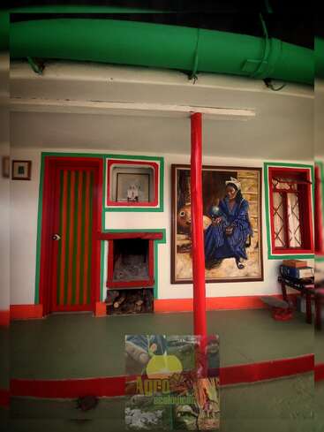 Cette chambre confortable dispose de cadres de porte colorés verts et rouges, d'une cheminée avec du bois, d'un tableau saisissant, de livres, d'une pipe verte et d'éléments de décoration rustiques.