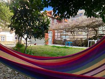The image depicts a serene backyard scene, featuring a vibrant hammock, lush greenery, and a charming house, evoking a sense of tranquility and relaxation.
