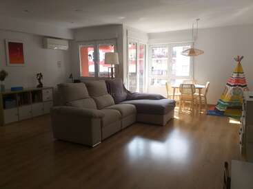 Le salon lumineux et ouvert est doté d'un canapé sectionnel beige, d'une table à manger, d'une tente de jeu pour les enfants, de planchers en bois, de grandes fenêtres et d'un décor minimaliste pour une ambiance chaleureuse.