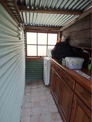 Cette photo montre une petite buanderie dotée d'un toit en tôle ondulée, d'une fenêtre dépolie, d'armoires en bois, d'un petit réfrigérateur, d'un sol carrelé et de divers bacs de rangement.