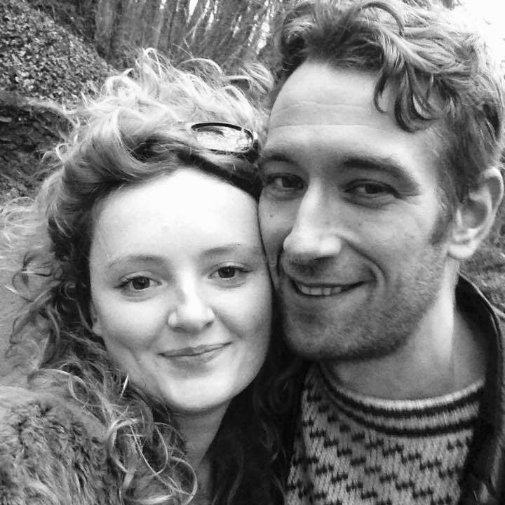 The image is a black-and-white selfie of a man and woman posing closely together, with the woman on the left and the man on the right.