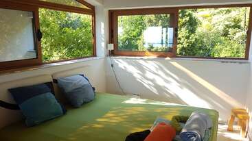 The image depicts a room with a large window, showcasing a serene scene of a table and chairs, with a bookshelf in the background, evoking a sense of calmness and tranquility.