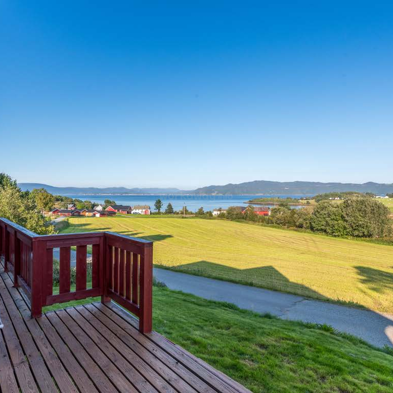 The image depicts a serene outdoor scene featuring a body of water, trees, and a house, with a grassy area and a wooden fence, evoking a sense of tranquility and natural beauty.