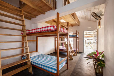 La imagen muestra una habitación con una cama y una mesa, una gran ventana y una puerta, probablemente con fines promocionales o de interiorismo. La distribución y el mobiliario de la habitación ocupan un lugar destacado.