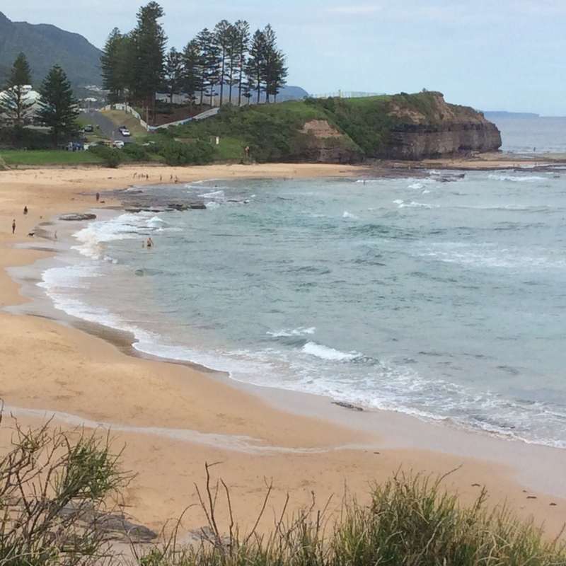 The image depicts a serene beach scene with a sandy shore, gentle waves, and a cliff in the background, evoking a sense of tranquility and natural beauty.