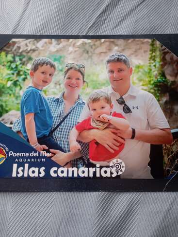 A happy family of four poses together at Poema del Mar Aquarium in the Canary Islands, smiling and enjoying their day out in a lush, green setting.