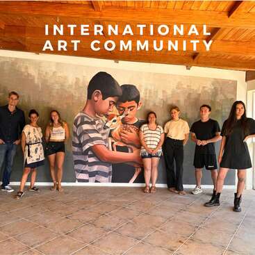 Das Bild zeigt eine Gruppe von Menschen, die vor einem großen Gemälde mit zwei Jungen stehen, die ein Rehkitz halten, und über ihnen steht "International Art Community".