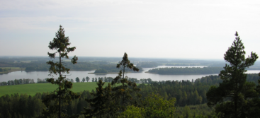 The image depicts a serene landscape featuring a lake, surrounded by trees and hills, with a clear blue sky above, evoking a sense of tranquility and natural beauty.