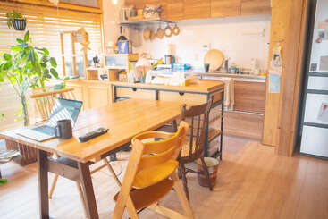 Cette cuisine chaleureuse et baignée de soleil est agrémentée de meubles en bois, de plantes d'intérieur et d'appareils électroménagers modernes. Un ordinateur portable et une tasse à café posés sur la table en font un espace de travail confortable à la maison.