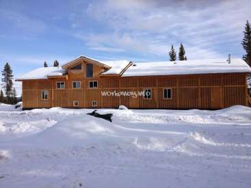 La imagen muestra una gran casa de dos plantas con tejado a dos aguas, situada en un paisaje nevado, con una marca de agua destacada en la que se lee "workaway.info".