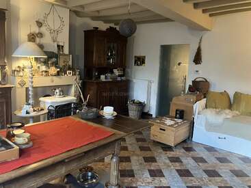 Dieses gemütliche Wohnzimmer hat rustikale Holzmöbel, einen dekorativen Kamin, eine eklektische Einrichtung, gemusterte Fußböden, ein bequemes Tagesbett mit Kissen und warmes, natürliches Licht. Entspannte Atmosphäre.
