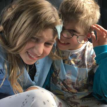 L'image représente deux enfants assis ensemble, la fille à gauche et le garçon à droite, tous deux regardant quelque chose.