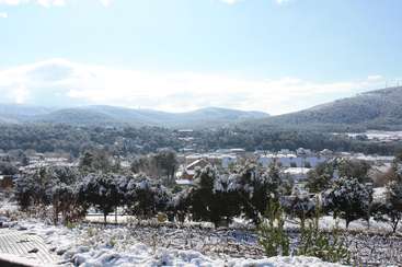 The image depicts a serene winter landscape, featuring a small town nestled among snow-covered trees and hills, with a clear blue sky above.